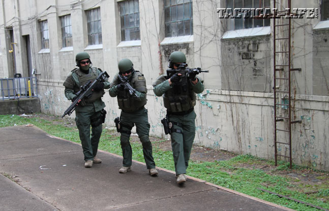 Operators equipped with REC7 Gen II rifles help their designated marksman, carrying a Barrett MRAD, into position. These rifles feature expertly applied Cerakote finishes for the ultimate in durability.