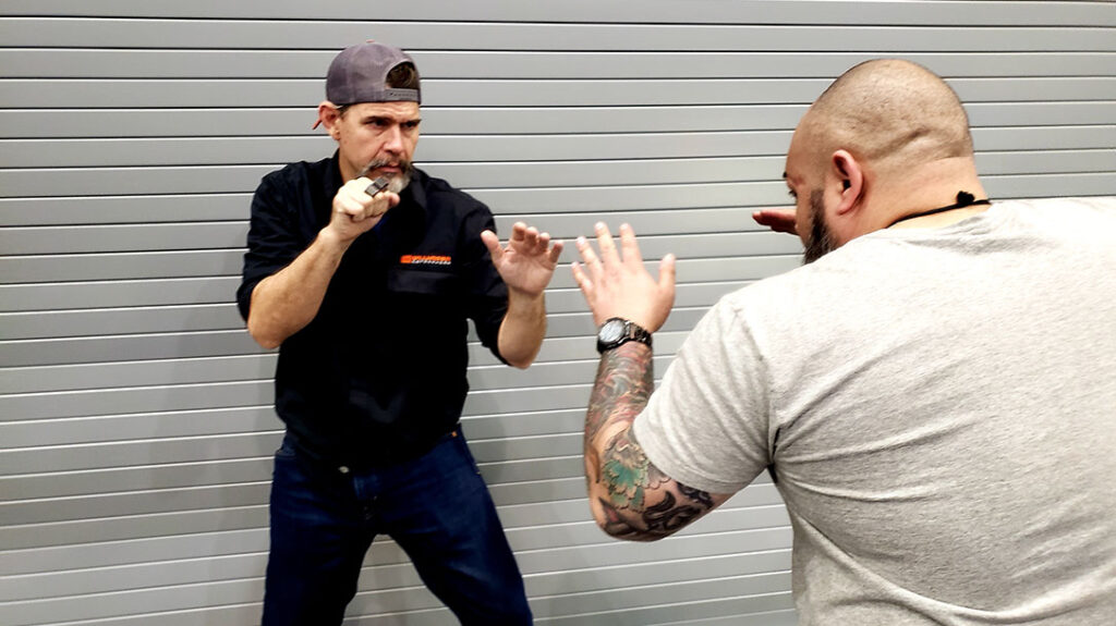 Proper Blocking: Jose, the would-be attacker, attempts to corner Chris against a wall. Both men have their guards up.