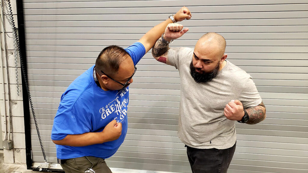 Proper Blocking: Frank decides to throw a looping left-overhand punch to the side of Jose’s head. Jose lunges in with a modified high block that counters the energy of Frank’s punch.