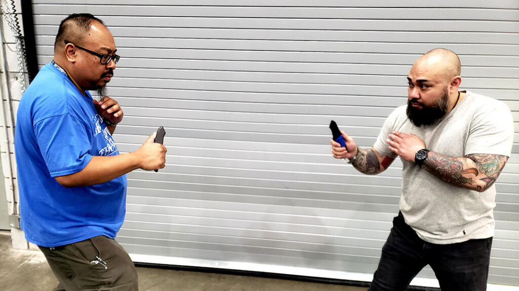 Proper Blocking: Jose draws a knife and squares up with Frank. Jose sizes him up as he starts to approach. Frank draws his own knife and prepares for an attack.