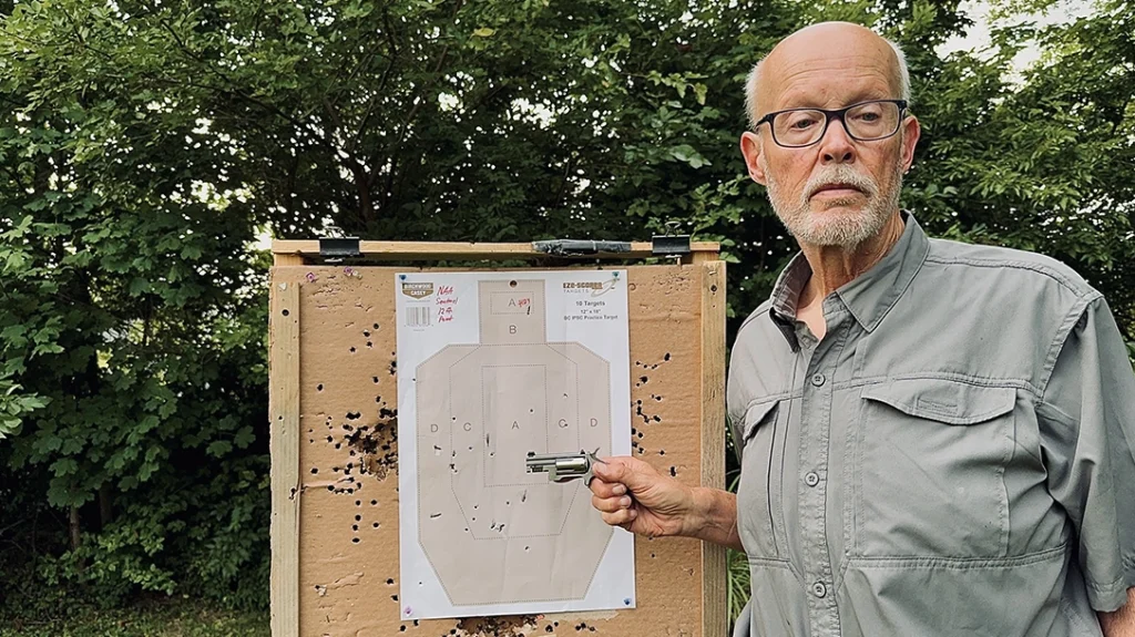 The author poses with the IPSC-type target that he used in a practical shooting exercise; you can see that some bullets key-holed into the target; shooting was rapid-fire.