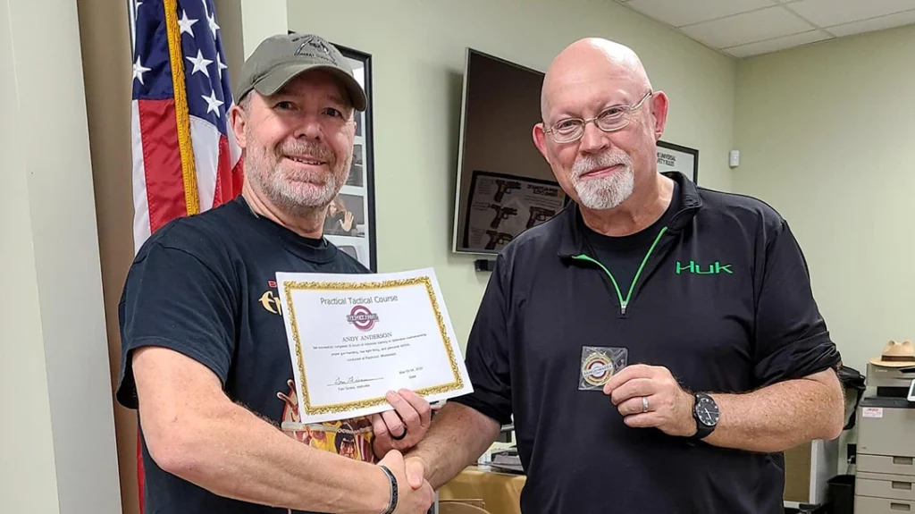 Tom Givens presents a certificate to a student.