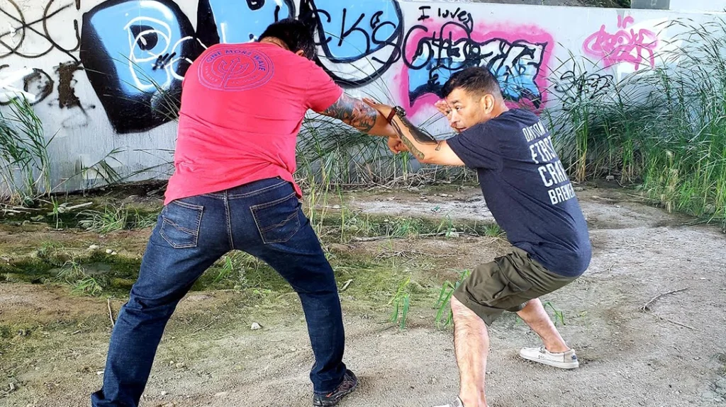 Sam attempts to throw a right punch, Johnny open palm blocks, and (Angle 2 V-Step) steps to the outside of the strike.