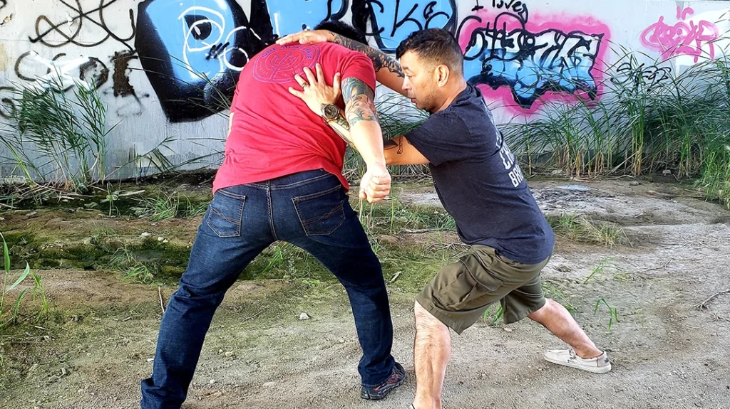 Basic Knee and Elbow Strikes: Johnny shoots in and slips his left hand under Sam’s arm while driving his right outer forearm into the side of Sam’s neck.