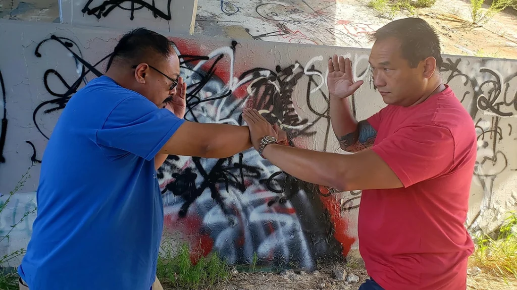 Basic Knee and Elbow Strikes: Frank attempts a right punch to Sam. Sam slaps the strike down with an open-handed parry.