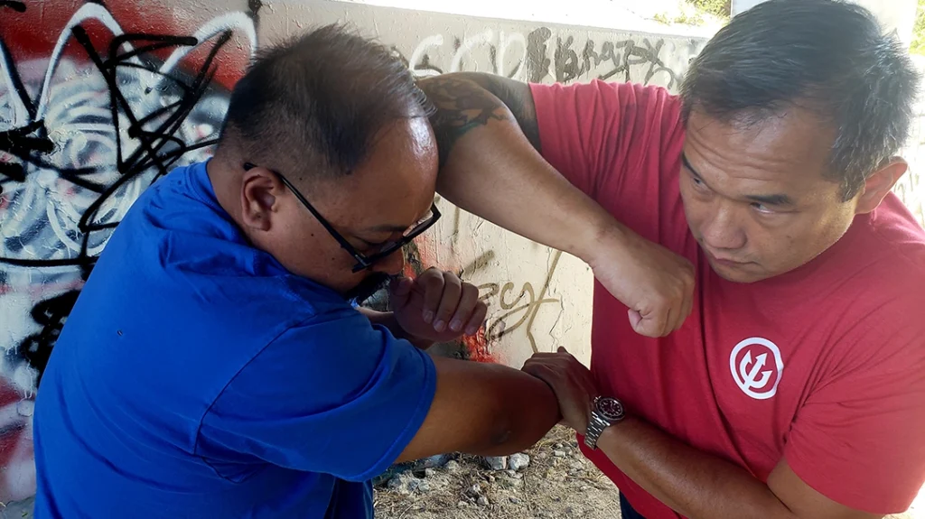 Pushing Frank’s attacking arm down and across his body to clear an opening.