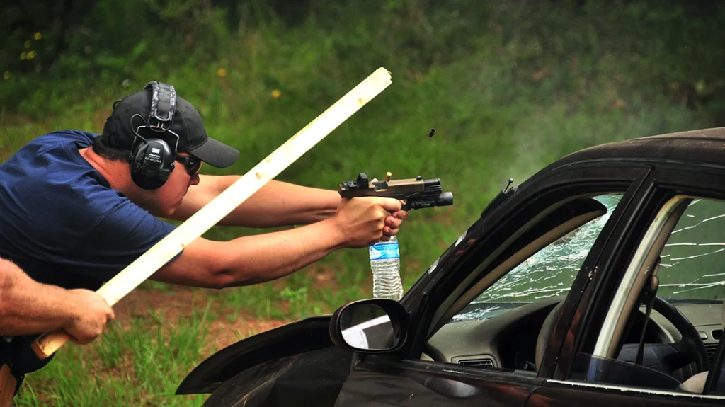 Modern optics for handguns are capable of surviving considerable impact abuse. The instructor is using a stick to foul the student's gun and cause stoppages.
