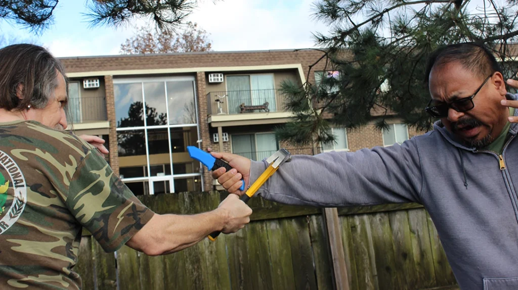 Improvised Vehicle Weapons: Don counters and strikes Frank’s arm with his hammer.