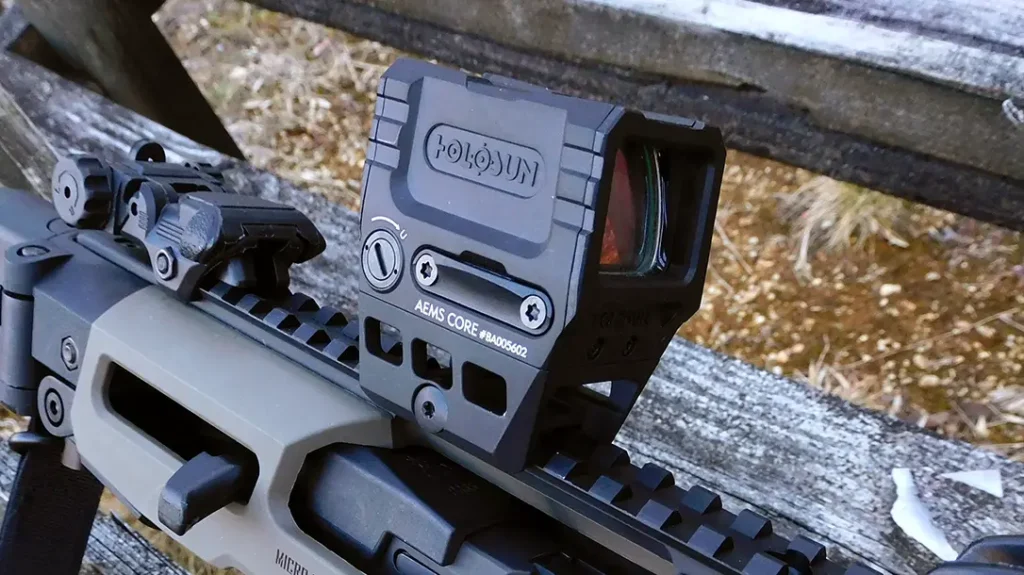 The author installed a Holosun AEMS Core enclosed emitter red dot, but the flip-up sights are co-witnessed, so he used both.