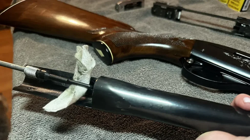 Field Stripping a Shotgun: Starting with the barrel, I attached a cleaning patch onto the cleaning rod and poured a couple of drops of the MC-7 Bore Cleaner onto the white cotton before I pushed the rod in towards the muzzle.