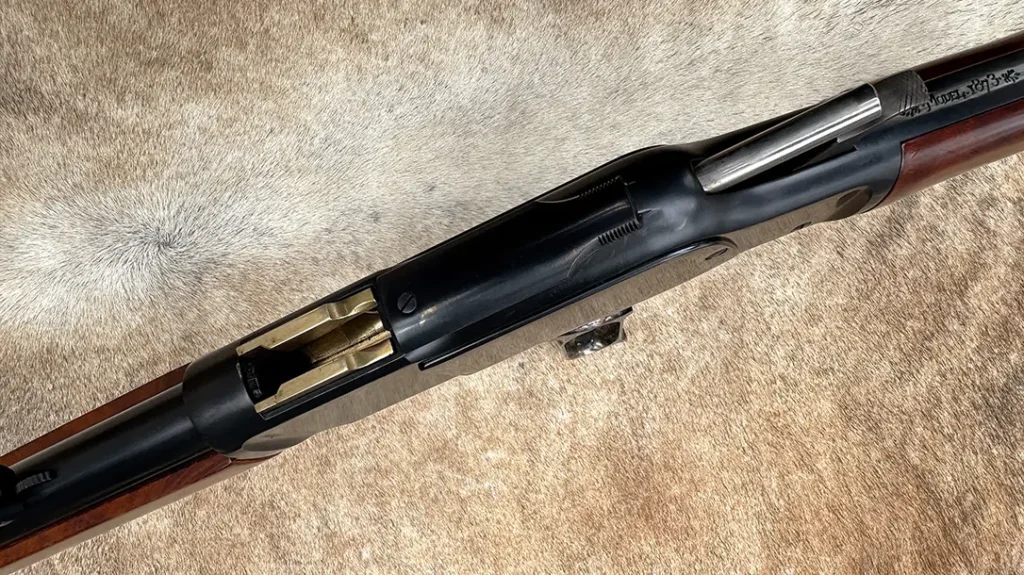 Looking at the top of the receiver with the lever swung down, the brass cartridge carrier, dust cover and bolt can be seen.