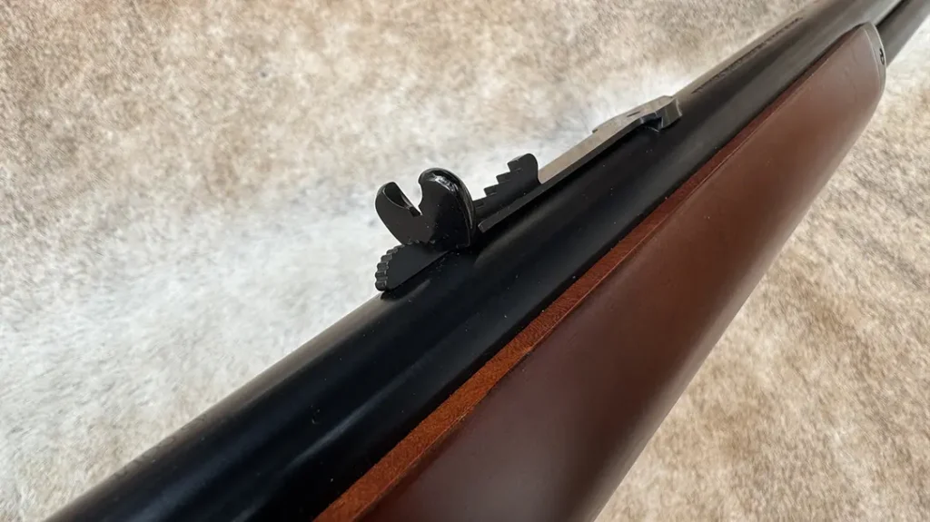 Affixed in a dovetail, the rear sight is a step-adjustable semi-buckhorn.
