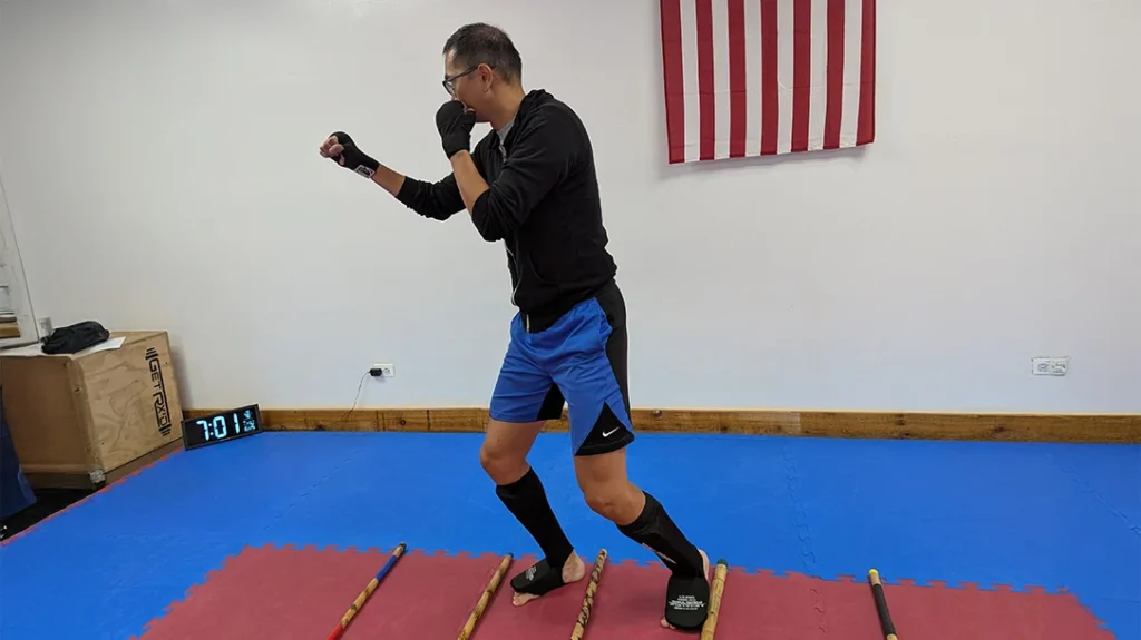 Adam lands forward, ready to throw a counter. Always return to, and maintain, a fighting position when moving forward or backward. Pay attention to how and where you are shifting your weight when you land, and try hard not to kick the sticks.